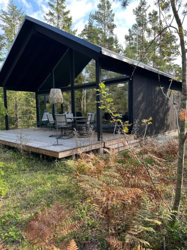 uma casa na floresta com um telhado preto em Maven Kustnära Stugor em Kappelshamn