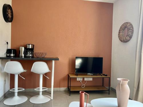 un salon avec deux tabourets blancs et une télévision dans l'établissement Studio Saint-Roch, à Montpellier