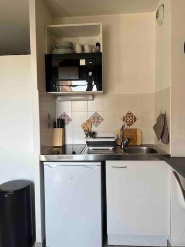 eine kleine Küche mit weißen Schränken und einem Waschbecken in der Unterkunft Studio Saint-Roch in Montpellier
