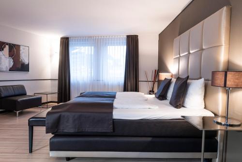 a bedroom with a large bed and a chair at Mauritius Hotel & Therme in Cologne