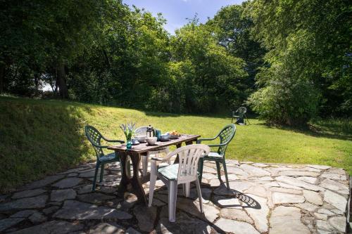 a wooden table with three chairs on a stone patio at Garden Cottage Newcastle Emlyn in Newcastle Emlyn