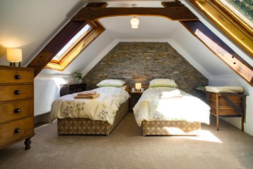 a attic bedroom with two beds and a stone wall at Garden Cottage Newcastle Emlyn in Newcastle Emlyn