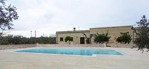 une villa avec une piscine en face d'un bâtiment dans l'établissement Masseria Pozzelle, à Otrante