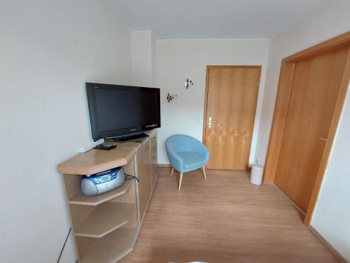 a living room with a television and a blue chair at Ferienwohnung Jäger in Viereth-Trunstadt