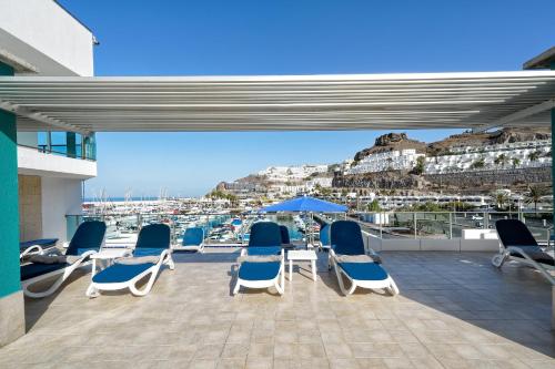 a group of chairs and umbrellas on a patio with a view at Morasol Suites in Puerto Rico de Gran Canaria