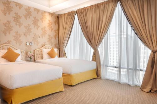a bedroom with two beds and a large window at Plaza Inn Doha in Doha