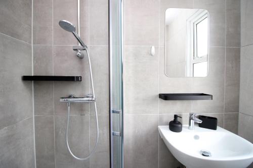 ein Bad mit einer Dusche, einem Waschbecken und einem Spiegel in der Unterkunft Entire 2 Bed Modern Flat with Parking For Families, Business and Contractors in Bristol