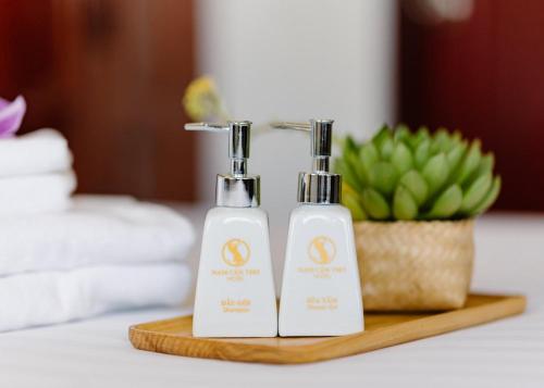 two bottles of soap on a wooden tray with a plant at NAM CẦN THƠ HOTEL in Ấp Phú Thạnh (4)