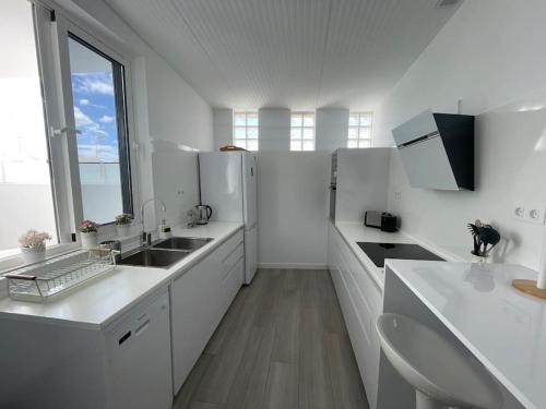 a white kitchen with white counters and a large window at White Serenity in Playa Honda