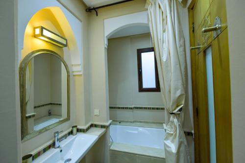 ein Badezimmer mit einer Badewanne, einem Waschbecken und einem Spiegel in der Unterkunft VILLA APPLE GARDEN RESORTS 45 MARRAKECH in Marrakesch