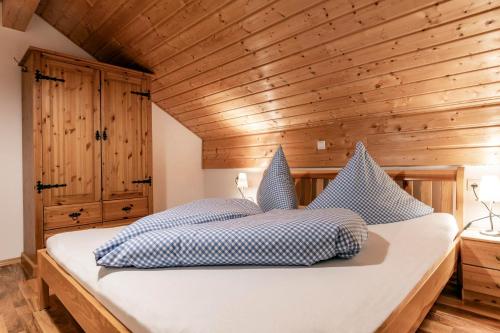 a bedroom with wooden walls and a bed with blue and white pillows at Haus Montanara myRelaxs in Tschagguns