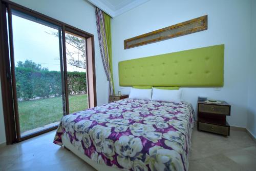 ein Schlafzimmer mit einem Bett und einem großen Fenster in der Unterkunft VILLA APPLE GARDEN RESORTS 45 MARRAKECH in Marrakesch