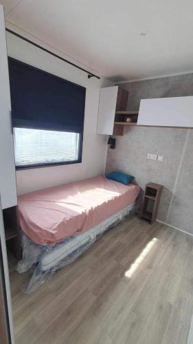 un petit lit dans une chambre avec une fenêtre dans l'établissement Mobil-Home MA 20 à Vias - La Carabasse - Camping Siblu avec piscine, à Vias