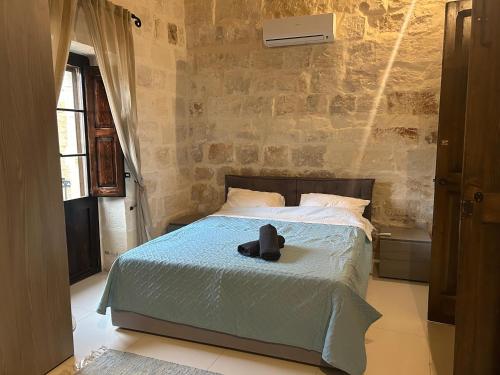 a bedroom with a bed with a hat on it at Traditional House of Character with Terrace - Central, Cozy & Calm in Birkirkara