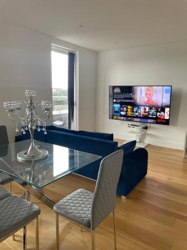 Luxury Top Floor Penthouse Apartment near Heathrow في لندن: غرفة معيشة مع طاولة زجاجية وتلفزيون