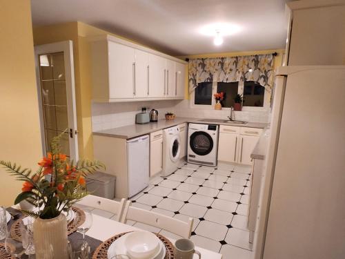 a kitchen with white cabinets and a washing machine at Meadow View in Elstow