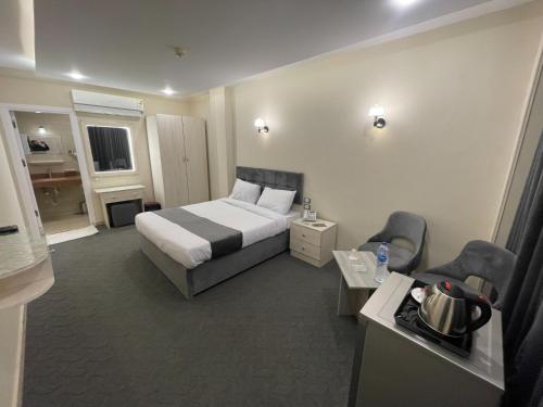 アスユートにあるHotel Royal Plazaのベッド1台と椅子2脚が備わるホテルルームです。