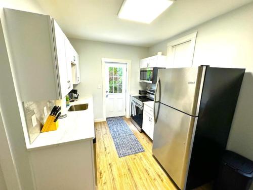 uma cozinha com um frigorífico de aço inoxidável e armários brancos em Cozy unit King bed & laundry em Wilmington