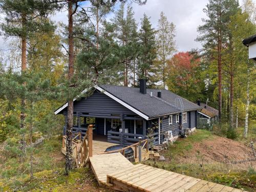 ein Haus im Wald mit einer Holzterrasse in der Unterkunft Matikkala Cottages in Ruokolahti