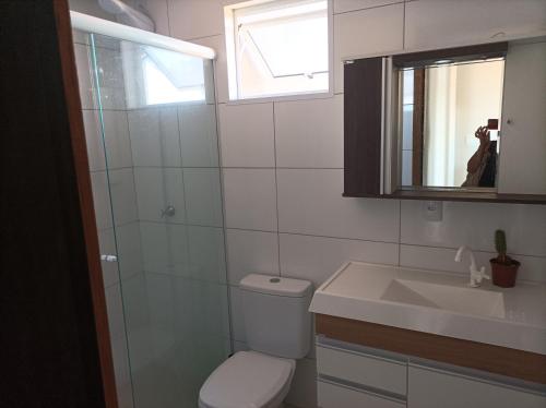 a bathroom with a toilet and a sink and a mirror at AP Beira mar in Laranjal