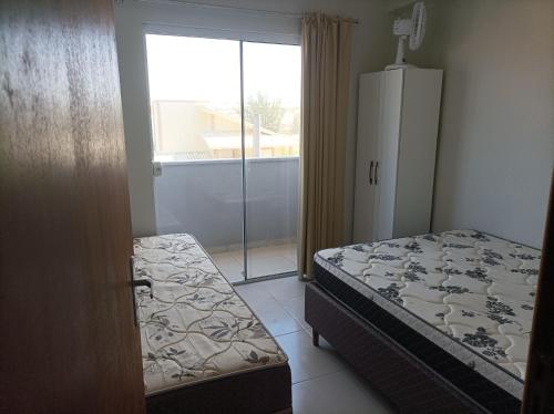 a bedroom with a bed and a sliding glass door at AP Beira mar in Laranjal