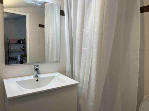 une salle de bain blanche avec un lavabo et un miroir dans l'établissement Le passage 75, à Montpellier