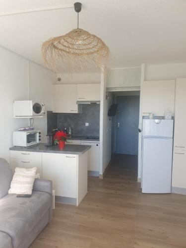 une cuisine avec des armoires blanches et un canapé dans une pièce dans l'établissement La petite Camargue, au Grau-du-Roi