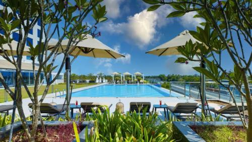 a swimming pool with chairs and umbrellas at O by Tamara, Trivandrum in Trivandrum