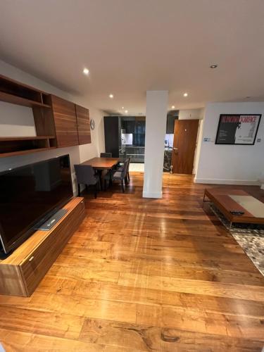 een woonkamer met een grote televisie en een houten vloer bij Exclusive Large Parliament Apartment in Londen