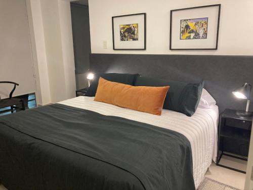 um quarto com uma cama preta e branca com uma almofada laranja em La pedrera Departamentos de lujo en la ciudad Cultural em San Salvador de Jujuy