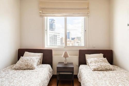 two beds in a room with a window at Warm Residence in the heart of the City Center - Balcony & view in Nicosia