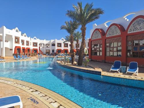 uma piscina num resort com cadeiras e palmeiras em Sharm Inn Amarein - Boutique Hotel em Sharm el Sheikh