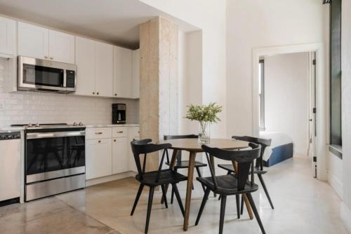 a kitchen with white cabinets and a wooden table and chairs at La Luz in San Antonio