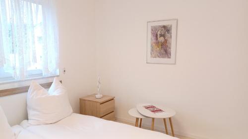 ein weißes Schlafzimmer mit einem Bett und einem Tisch in der Unterkunft Ferienwohnung Mioritza in Kallmünz