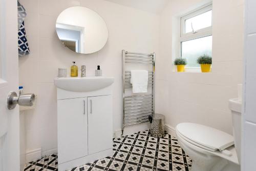 a white bathroom with a sink and a toilet at Luxury 3BR House - Free Parking and Stunning Garden! in Nottingham