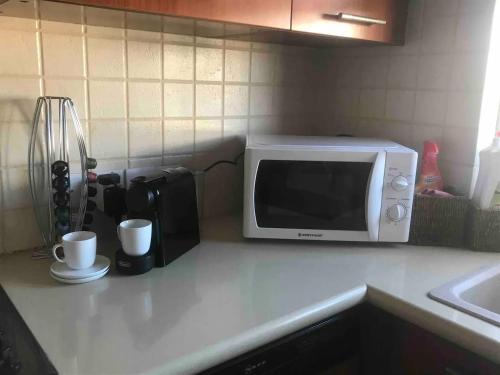 a microwave on a kitchen counter with two cups at Warm Residence in the heart of the City Center - Balcony & view in Nicosia