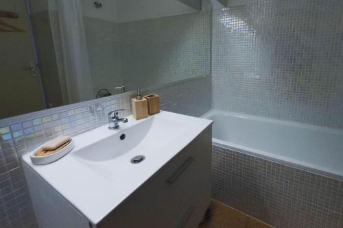 La salle de bains est pourvue d'un lavabo blanc et d'une baignoire. dans l'établissement La maison du pêcheur, à Palavas-les-Flots