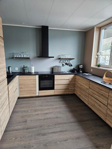a large kitchen with wooden cabinets and a window at Apartment Isfjordsveien in Åndalsnes