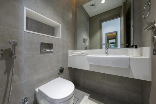 La salle de bains est pourvue de toilettes blanches et d'un lavabo. dans l'établissement Dar Alsalam - Modern Comforts in Dubai District One Residence 29, à Dubaï