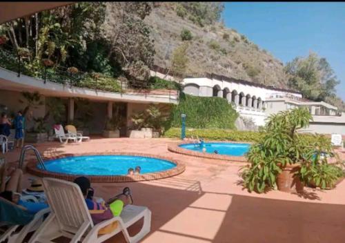 a group of people sitting in chairs by a swimming pool at Tiny house Taormina mare with sofa bed - mini stanza Taormina mare con divano letto in Taormina