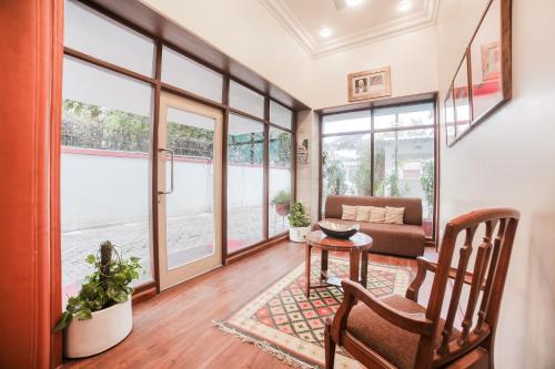 ein Wohnzimmer mit Fenstern, einem Tisch und einem Sofa in der Unterkunft Super Townhouse 1267 Dayal Lodge - A Boutique Hotel in Agra