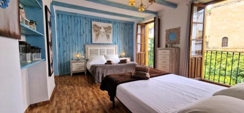 2 camas en una habitación con paredes y ventanas azules en DS Casa San Fernando, en Córdoba