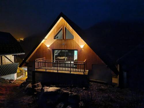a large wooden house with a deck at night at Chalet côté montagne in Oz