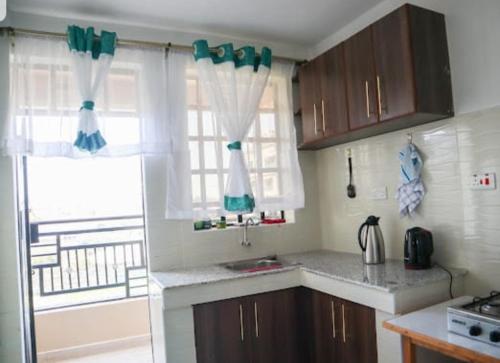 una cocina con armarios marrones y una ventana con cortinas en bluesky en Nairobi
