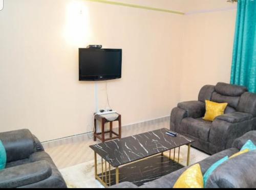 sala de estar con 2 sofás y TV de pantalla plana en bluesky en Nairobi