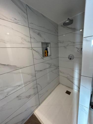 La salle de bains est pourvue d'une douche et de murs en marbre blanc. dans l'établissement Jardin secret en plein cœur du Cabot, à Marseille