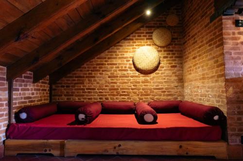 a red couch in a room with a brick wall at Manju Baha Hotel & Restaurant in Bhaktapur