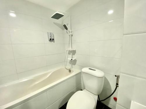a white bathroom with a toilet and a bath tub at Amura Hotel Thủ Đức in Ho Chi Minh City