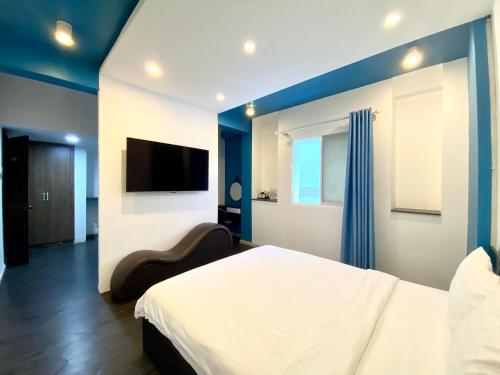 a bedroom with a white bed and a tv at Amura Hotel Thủ Đức in Ho Chi Minh City