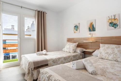 a bedroom with two beds and a window at Apartamento Suite Arco Solo Parejas in Conil de la Frontera